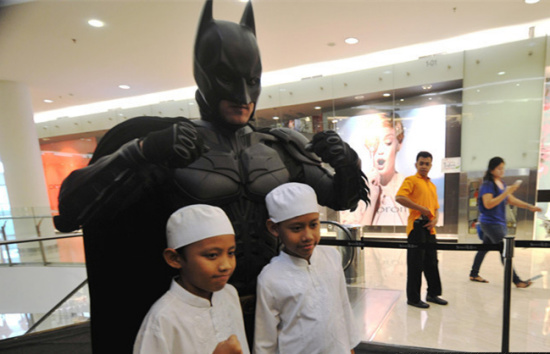 Children pose with a man wearing costumes of animation character of Batman at a shopping center as part of Batman 75th anniversary exhibition in Jakarta, Indonesia, June 27, 2014. (Xinhua file photo/Agung Kuncahya B.)