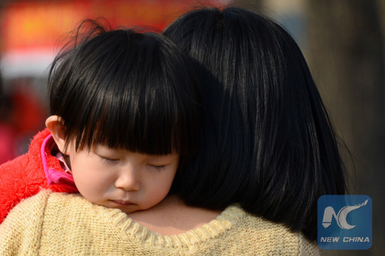 A child sleeps on the shoulder of a woman in Jinan, capital of east China's Shandong Province, March 16, 2015. March 21 is the 15th World Sleep Day. (Xinhua/Guo Xulei)