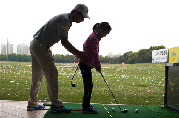 A girl practices under the guidance of a coach at the Yao Shine Golf School in Shanghai on April 9. A growing number of primary schools in the city have put the game on their curriculums as an option for PE lessons or as an afterschool activity.GAO ERQIANG/CHINA DAILY