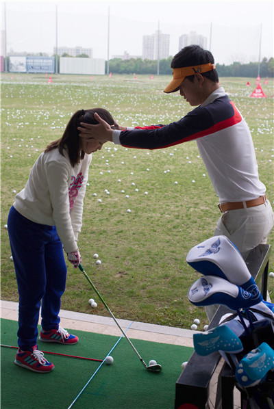 A girl practices under the guidance of a coach at the Yao Shine Golf School in Shanghai on April 9.GAO ERQIANG/CHINA DAILY