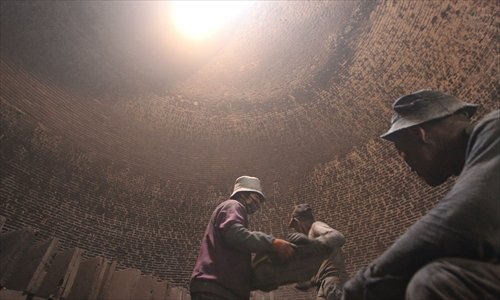 Workers load bricks from inside the kiln as light floods in from a hole at the top. (Photo: Yang Hui/GT)