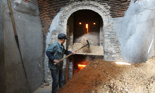 A worker adds wood chips to the furnace. (Photo: Yang Hui/GT)