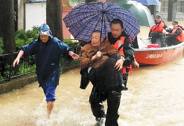 Armed Police Force officers help evacuate stranded local people in the wake of a massive landslide which trapped more than 40 people in Sanming, Fujian province, on Sunday. ZE XIN / FOR CHINA DAILY