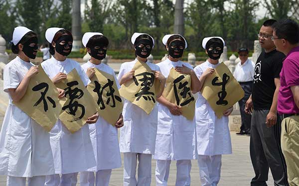 Nurses from a hospital in Cangzhou, Hebei province, hold placards that say 'Don't vilify doctors' at an event on Tuesday. The event calls for protection of medical workers and a harmonious relationship between patients and doctors.(Fu Xinchun/For China Daily)