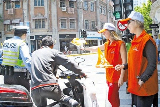 Two Russian women help a police officer as he apprehends a man for a traffic violation in Jingan yesterday. Earlier in the day, 40 foreigners who work in the district attended a seminar to help them master the finer points of Shanghais traffic laws.(Dong Jun)