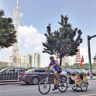 Qi Hailiang cycles with his daughter and dog, who sit in a special made carriage chained to the back wheel of his bicycle. (Photo from Yanzhao Metropolis Daily)
