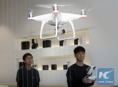 A staff member of major Chinese consumer-drone maker DJI shows Phantom 4, the latest consumer quadcopter camera (or drone) introduced by DJI last week, at DJI's flagship store in Seoul, capital of South Korea, on March 11, 2016. (Photo: Xinhua/Yao Qilin)
