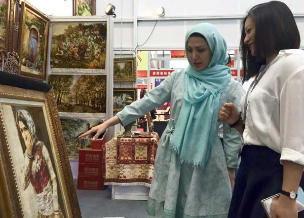 An Iranian cultural representative shows a tapestry to a Chinese buyer at the 12th China (Shenzhen) International Cultural Industries Fair, which opened Thursday in Shenzhen. (Photo by Qiu Quanlin/chinadaily.com.cn)