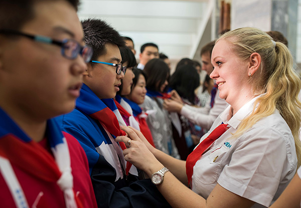 A staff member at a study camp in Krasnodar, Russia, helps a Chinese student with his uniform. EVGENY SINITSYN/XINHUA