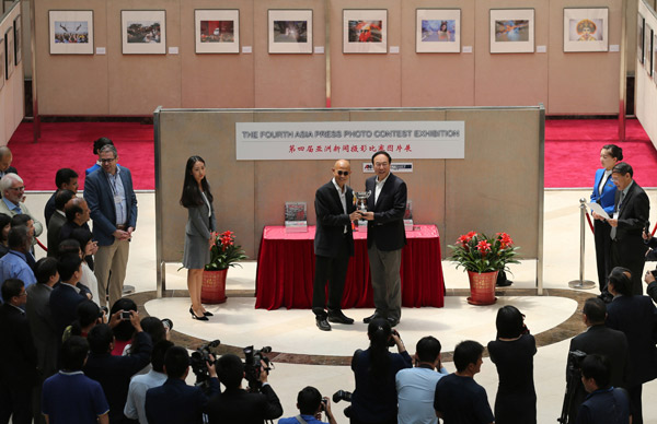 hu Ling (center right), publisher and editor in chief of China Daily, presents a winner's trophy to Suthichai Yoon, chief adviser of Nation Multimedia Group, whose staff won two top prizes in the fourth Asia Press Photo Contest on Monday in Beijing. (WANG ZHUANGFEI / CHINA DAILY)