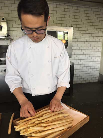 Chef Steve Zhang prepares white asparagus for dishes at Feast restaurant in Beijing's East hotel. (Photo provided to China Daily)