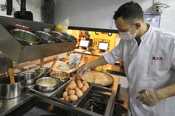 American Jeff Torres makes jianbing at a kitchen of Huangtaiji, a food chain built on the humble egg pancake. (Photo by Wang Zhuangfei/China Daily)