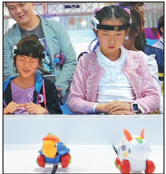 Two children maneuver a toy rabbit and a toy turtle, both controlled by brain wave devices, during a race in Beijing on Saturday at the 2016 Science and Technology Week.Wang Zhuangfei / China Daily