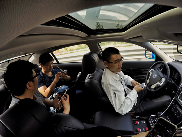 Engineers watch videos on their smartphones during a test journey from Chongqing in southwestern China to Beijing in April. The car used was an autonomous sedan developed by Chang'an Automobile Group.CUI LI/CHINA DAILY