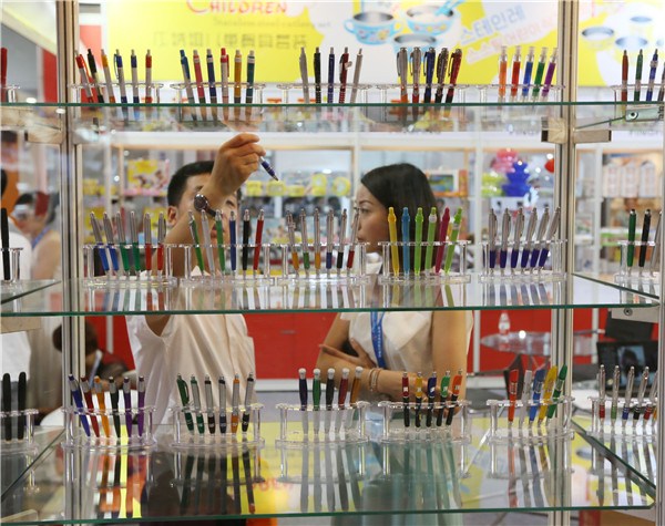 Customers pick pens at an international gift fair in Beijing. A JING/CHINA DAILY
