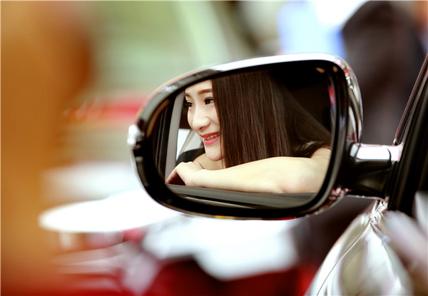 A woman checks a new model's mirror during a recent auto fair in Yichang, Hubei province. The MPV segment has been growing rapidly in the past three years.LIU JIAO/CHINA DAILY
