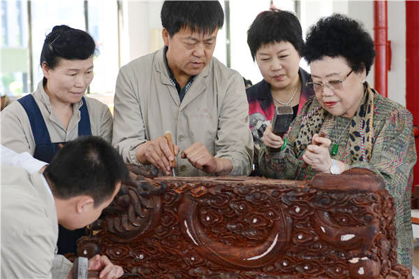 Chan Laiwa (right) visits the craftspeople working on a red sandalwood piece at a workshop of the Red Sandalwood Museum in Beijing. Photos provided to China Daily