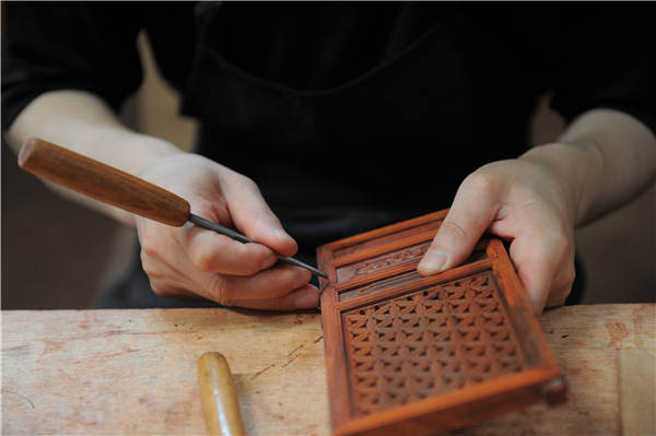 A craftsman carves on a wooden structure of an old Beijing watchtower replica.