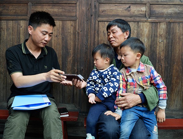 Song Minghong (left), a government employee in Huarong village, Hunan province, records information about Duan Zeben's grandsons for the country's first national survey of left-behind children. LIU JIE/XINHUA/ZHU WENBIAO/CHINA DAILY