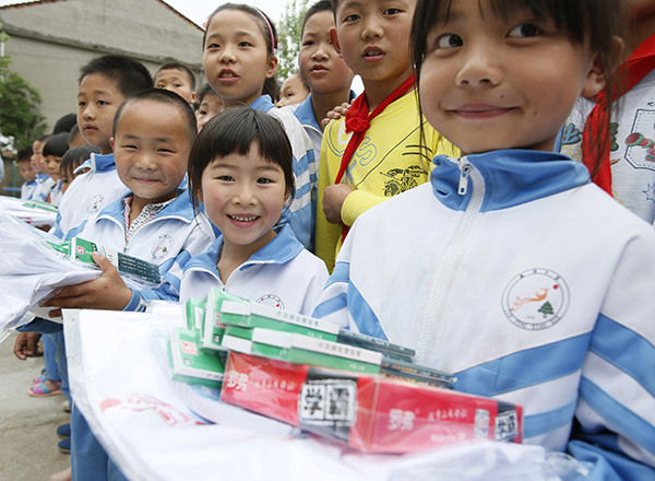 The children of migrant workers in Hujia village, Jiangxi province, receive gifts in advance of Children's Day, which falls on June 1. LIU JIE/XINHUA/ZHU WENBIAO/CHINA DAILY