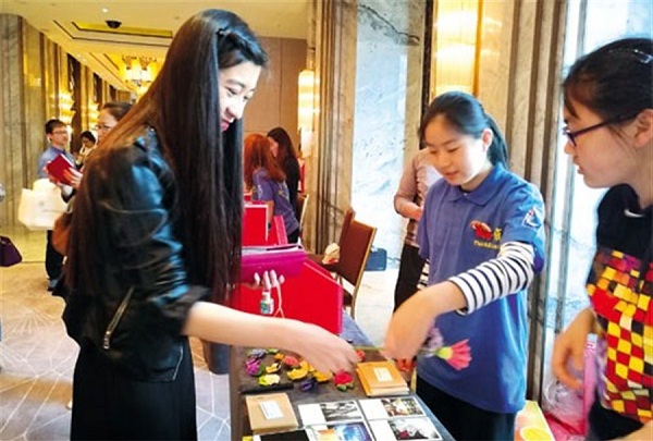A young woman buys a handicraft at a charity bazaar staged to raises funds to help families with missing children.(Photo/Shanghai Daily)