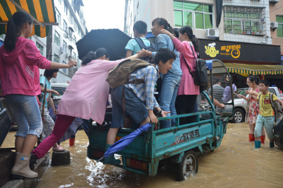 People climb onto a motorized tricycle to get around after heavy rain in Ningde, Fujian province, on June 2, 2016. (Photo/China News Service)