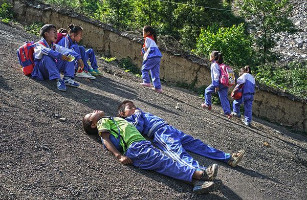 Children from Atuler village in Sichuan province take a rest during their regular long trudge to school. CHEN JIE/ FOR CHINA DAILY