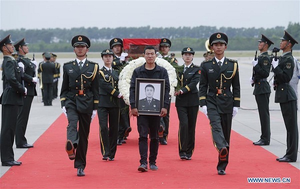 Shen Mingming (C), elder brother of Chinese UN peacekeeping soldier Shen Liangliang, escort the coffin of Shen Liangliang to the hearse at Longjia Airport in Changchun, capital of northeast China's Jilin Province, June 9, 2016. The body of Shen Liangliang, who was killed in a terrorist attack in Mali last month, arrived in northeast China's Changchun City on Thursday afternoon. (Xinhua/Yin Gang)