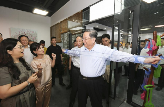Yu Zhengsheng (2nd L) experiences a chest-expander made by start-ups of young entrepreneurs from Taiwan during a visit to the cross-Strait innovation and entrepreneurship base for youth located in Haicang district of Xiamen,Fujian Province, June 11, 2016. (Xinhua/Ding Lin)