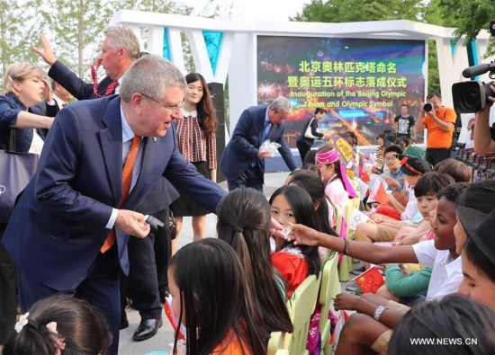International Olympic Committee President Thomas Bach (L, Front) presents a child a gift after the opening ceremony of the Beijing Olympic Tower in Beijing, capital of China, on June 12, 2016. (Photo/Xinhua)
