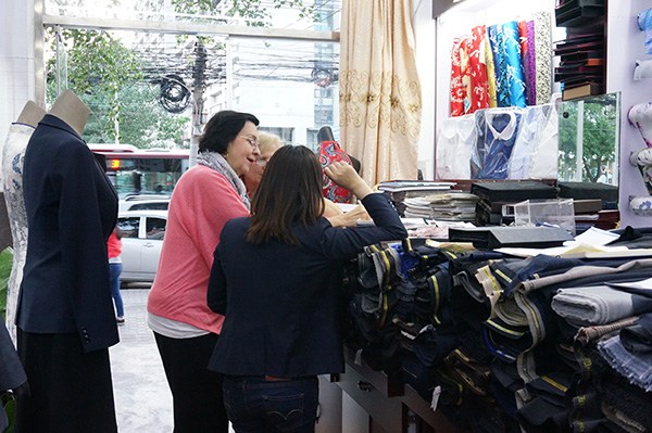Yan Yuxiang bargains in fluent English with a new foreign customer introduced by a return customer in her shop in Beijing in May 2016. (Photo/chinadaily.com.cn)