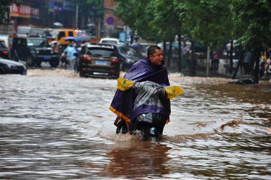 A man rides on a waterlogged road after a heavy rainfall in Zhuzhou City, central China's Hunan Province, June 15, 2016. (Photo: Xinhua/Long Hongtao)