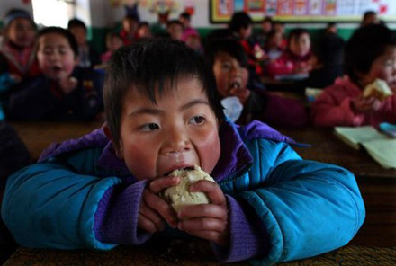 A boy eats cold steamed buns at school in Xiji county, Ningxia on Feb. 23, 2011. (File photo/Xinhua)  