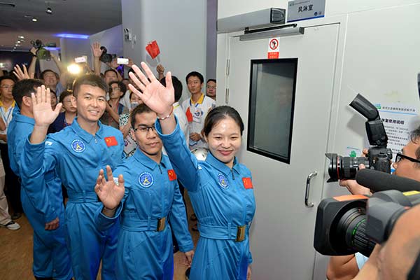 Four volunteers wave to the cameras before starting a six-month living experiment in an enclosed space capsule in Shenzhen, Guangdong province, on Friday. The project is designed to support China's deep-space exploration plan. (Photo/Xinhua)