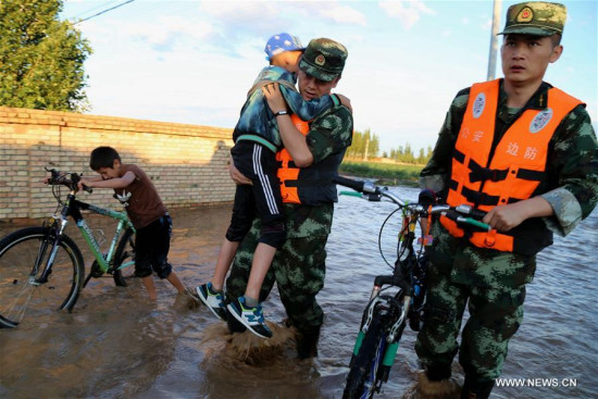  Soldiers rescue two trapped children after a flood submerges dozens of villages in Mongolian Autonomous Prefecture of Bortala, northwest China's Xinjiang Uygur Autonomous Region, June 19, 2016. A torrential rainfall triggered a flood in Bortala on Sunday. (Xinhua/Zhang Jia)