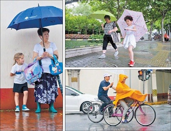 People brave the first storm of the plum rain season yesterday. Forecasters said locals should prepare for sweltering weather with intermittent rains.(Dong Jun)