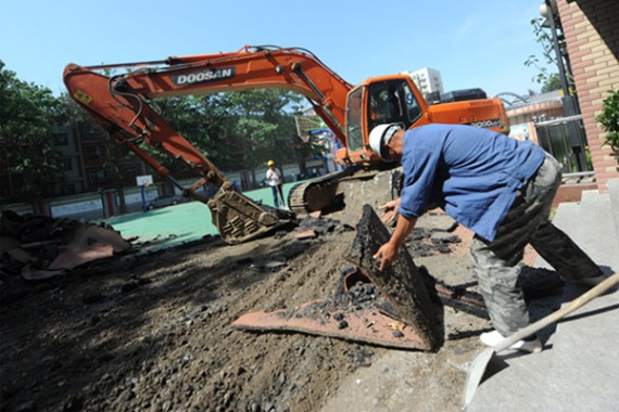 A synthetic running track is dug up at a school in Beijing last week. (Photo: China Daily/Weitong)