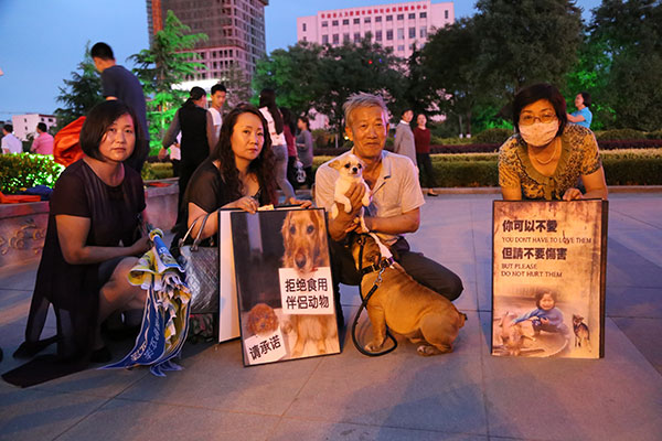 Dog lovers holding photos against dog abuse call for people to protest the Yulin dog meat festival, in Pingliang, Gansu province, on Monday. (Photo by Zheng Bing/China Daily)