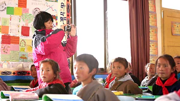 Wang Xiaoping visits a school, which uses a textbook compiled by her project, in Sichuan province. CHINA DAILY
