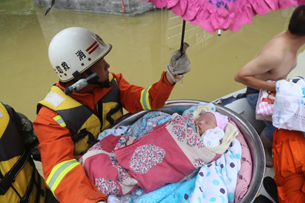 A rescuer escorts a sleeping 10-month-old infant to safety on Tuesday in Xiaba, a village in Guizhou province that has been left submerged by consecutive heavy downpours. (KE YOUCHUAN/CHINA DAILY)