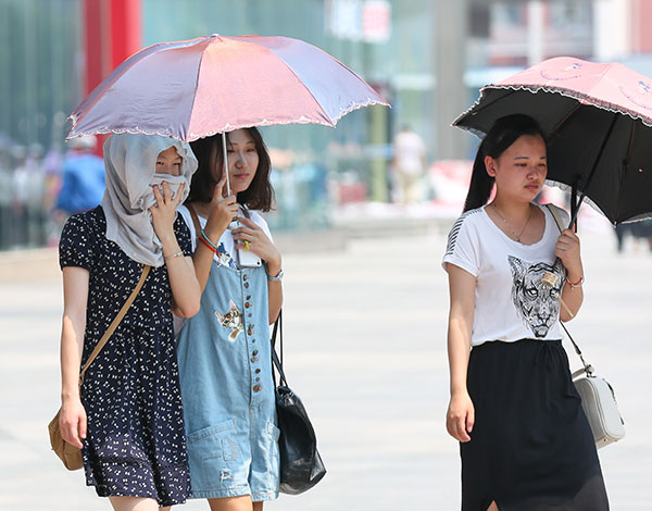 People protect themselves from the sun in Zhengzhou, Henan province, as the temperature in the city hit a high of 38 C on Wednesday. (Photo/China Daily)