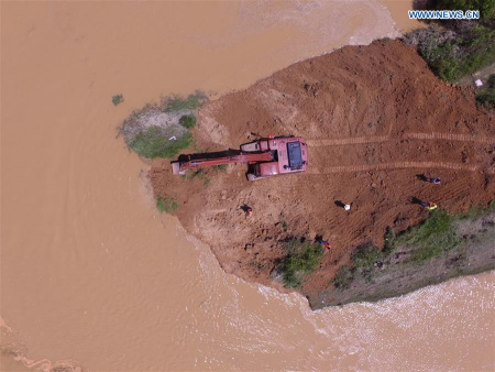 An excavator fills up a breach at Xiangyang dyke in Poyang County, east China's Jiangxi Province, June 22, 2016. About 500 armed police started to mend a 100-meter gap in the river defenses on Wednesday. (Xinhua/Zhou Mi) 
