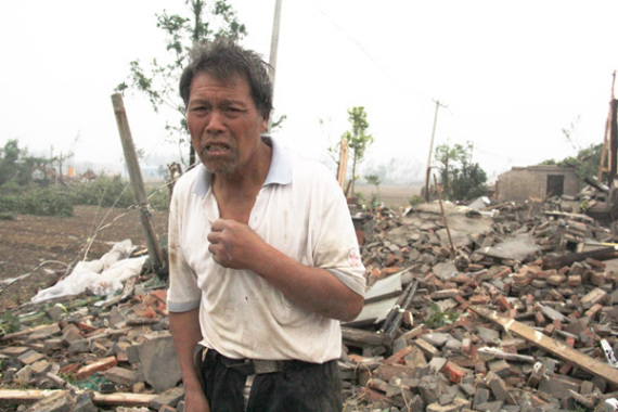 A villager stands in front of his house, which was leveled by the tornado and a hailstorm in Yancheng, Jiangsu province. (Photo: China News Service/Gu Hua)