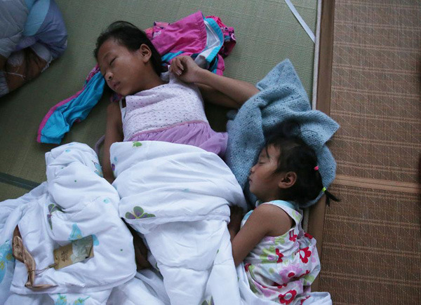 Two girls sleep at a temporary settlement in a primary school of Shuoji town, Funing county in Yancheng, Jiangsu province, on June 24, 2016. (Photo/Xinhua)
