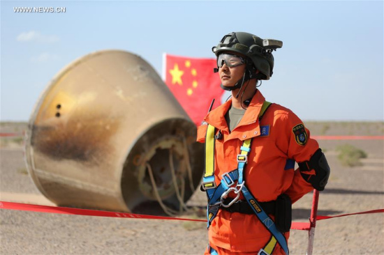 A search team member stands guard by the reentry module in Badain Jaran Desert in north China's Inner Mongolia Autonomous Region, June 26, 2016. The reentry module aboard carrier rocket Long March-7 was successfully recovered on Sunday. (Xinhua/Ju Zhenhua) 