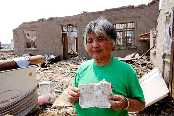 Chen Xiu, 74, shows her residence booklet, which was found amid the debris of her house. She and her husband survived the tornado by huddling in a corner of the house. KUANG LINHUA / CHINA DAILY