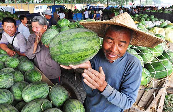 Farmers choose watermelons for their customers by tapping the produce at a wholesale market in Zouping county, Shandong province.(Dong Naide/For Chian Daily)