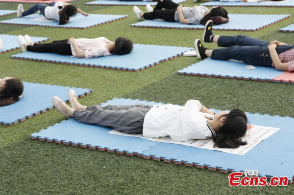 students lie on a playground during an event at a university in Wuhan City, the capital of Central China's Hubei Province, May 25, 2016. The event was organized by the university's psychology association and was aimed at raising awareness of sleep quality among students and the benefits of forming healthy habits. (Photo: China News Service/Liu Yongzhi)