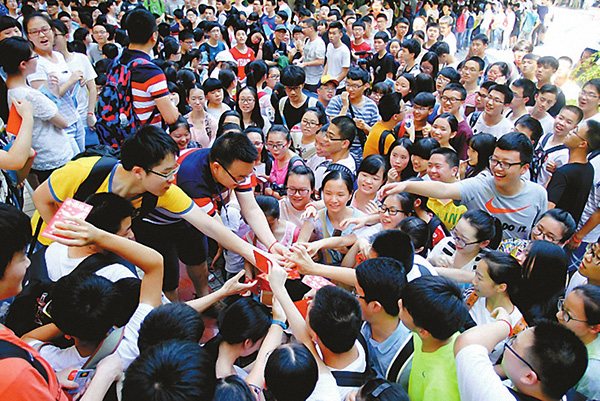 Students receive red envelopes from their teachers, wishing them good luck on the exam in Chongqing on Monday. QIAN BO/CHINA DAILY