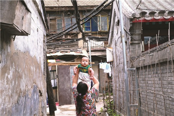 A woman from Anhui province plays with her baby in Beijing's Hongfu Hutong. The hutong is home to many migrant workers from outside the capital and, like many such neighborhoods, has infrastructure challenges. Zou Hong / China Daily